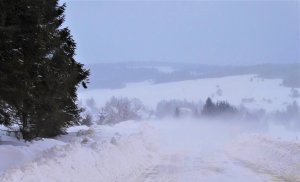 zima, zaśnieżona droga w tle zabudowania