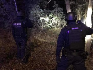 dwóch umundurowanych policjantów patroluje nocą las