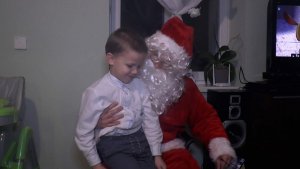 funkcjonariusz przebrany za Mikołaja wręcza prezent 5 letniemu chłopcu
