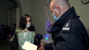 umundurowany funkcjonariusz wręcza prezent oraz kartkę z życzeniami matce małoletnich  dzieci
