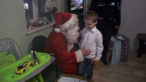 Funkcjonariusz przebrany za Mikołaja pozuje do zdjęcia z 5–letnim chłopczykiem