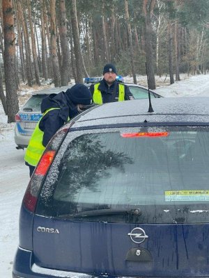 1. Policjanci podczas kontroli drogowe. Pora dzienna okres zimowy widoczny wokół śnieg