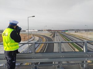 policjant mierzący z miernika na wiadukcie nad uatostradą