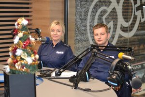 Policjantka i policjant ruchu drogowego w studiu radiowym siedzą przy mikrofonach udzielając wywiadu na temat bezpieczeństwa na drogach.