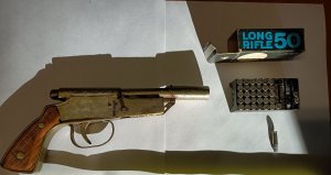 pistolet konstrukcji metalowej z drewnianą rękojeścią oraz pudełko z amunicją