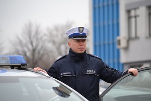 policjant ruchu drogowego  przy otwartych drzwiach radiowozu