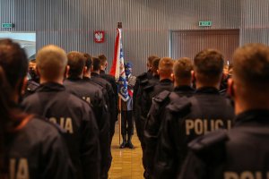 policjanci podczas ślubowania, w tle sztandar KWP w Krakowie