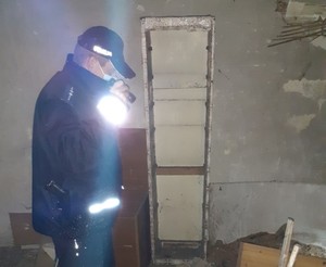 KPP Oświęcim Policjant w ramach akcji zima sprawdza opuszczony budynek używając latarki
