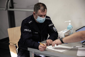 policjant przy biurku wypełnia dokument