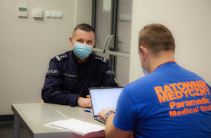 dowódca Oddziału Prewencji Policji przy biurku z ratownikiem medycznym