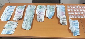 Banknoty i małe woreczki strunowe z białym proszkiem leżące na biurku