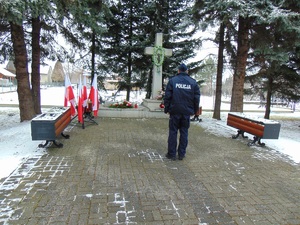 KPP Oświęcim. Zabezpieczenie 77 rocznicy wyzwolenia Auschwitz policjant oddaje hołd przed pomnikiem