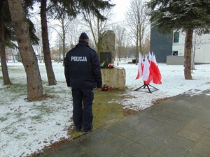 KPP Oświęcim. Zabezpieczenie 77 rocznicy wyzwolenia Auschwitz policjant .oddaje hołd przed pomnikiem