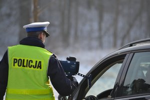 policjant ruchu drogowego wskazuje pomiar prędkości kierowcy