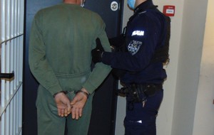 Policjant doprowadza zatrzymanego