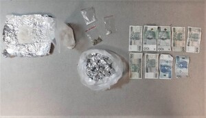 białe kryształki  w zwitkach folii aluminiowej, susz w woreczku strunowym, obok banknoty