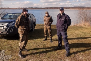 funkcjonariusze straży rybackiej i policjant przy stawie
