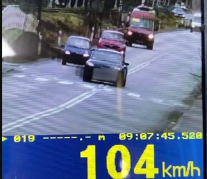 pojazd wyprzedzający inny na przejściu dla pieszych a po d nim miernik prędkości 104 km/h