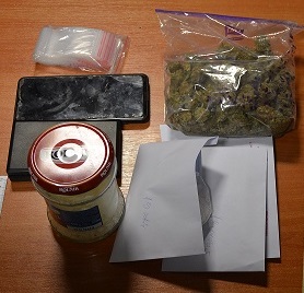 narkotyki w worku foliowym, słoiku obok waga i telefon oraz szara koperta leżą na stole