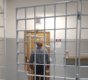zatrzymany stoi przodem do drzwi w pomieszczeniu dla zatrzymanych