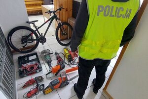 rower i elektronarzędzia na ziemi. Obok policjant w żółtej kamizelce