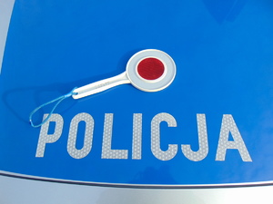 Maska radiowozu policyjnego, na którym leży tarcza do zatrzymywania pojazdów