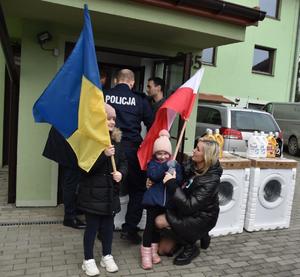 dziewczynki z Ukrainy trzymające flagi Polski i Ukrainy na tle policjanta
