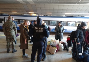 policjant rozmawia z podróżnymi na krakowskim dworcu