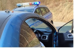 samochód osobowy z otwartymi przednimi drzwiami pasażera a naprzeciwko oznakowany radiowóz