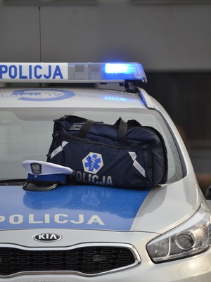 na oznakowanym radiowozie policyjnym leży torba medyczna oraz biała czapka policjanta ruchu drogowego