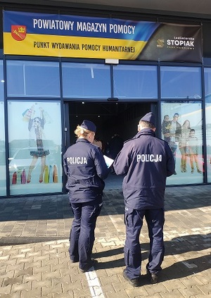 policjanci przed budynkiem magazynu pomocowego
