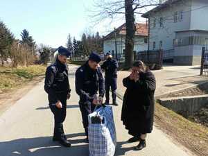 policjanci pomagają kobiecie nieść siatę