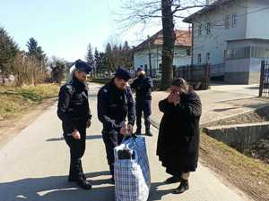 policjanci pomagają kobiecie nieść siatę