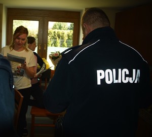Policjant oraz kobiety czytające ulotki informacyjne