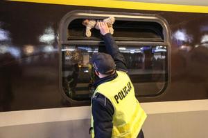 policjant przez okno pociągu przekazuje miśka