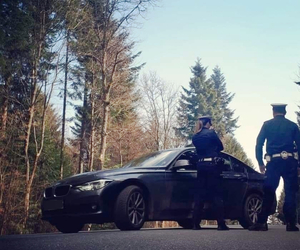 nieoznakowany radiowóz, obok policjanci odwróceni tyłem