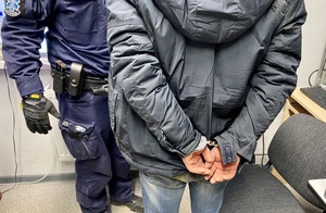 sprawca kradzieży samochodu z założonymi na ręce kajdankami