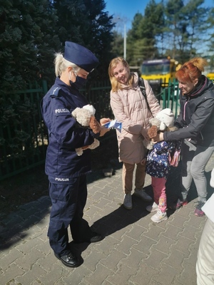 Policjantka najmłodszym ukraińskim dzieciom wręcza misie a ich mamą ulotkę informacyjną
