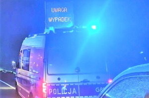 zdjęcie ilustracyjne policyjny radiowóz błyskające lampy na dachu napis Uwaga wypadek