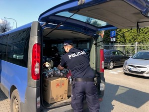 policjant pakuje do samochodu  walizki dla uchodźców