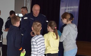 komendant powiatowy wręczający nagrody uczniom za konkurs w BRD, za nim stojący policjanci