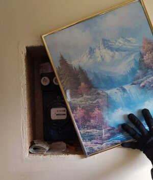 Za obrazem, w ścianie, gdzie znajduje się licznik prądu ukryty plik pieniędzy