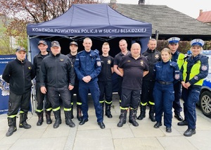 pozujący do zdjęcia policjanci i strażacy przy stoisku kpp sucha beskidzka