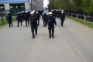 Oddział policjantów w umundurowaniu służbowym zmierza w kierunku stadionu