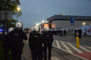 Policjanci w umundurowaniu służbowym stoją wzdłuż stadionu