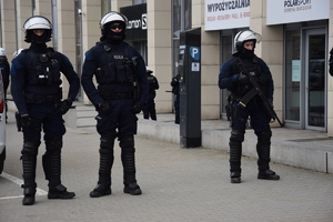 Trzej zamaskowani policjanci stoją w rejonie stadionu