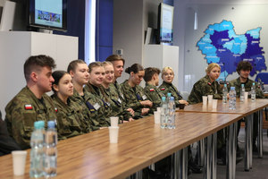 uczniowie klasy mundurowej siedzą przy stoliku na sali w KWP