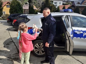 policjant przekazuje dziewczynce maskotkę