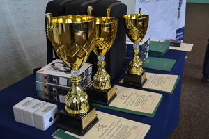 Puchary, dyplomy i nagrody ustawione na stole.