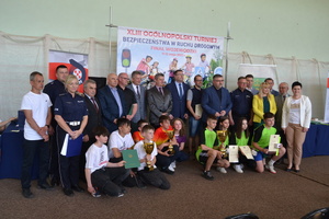 Na scenie stoją wyróżnieni zawodnicy z pucharami, nagrodami i dyplomami wraz z osobami wręczającymi nagrody,